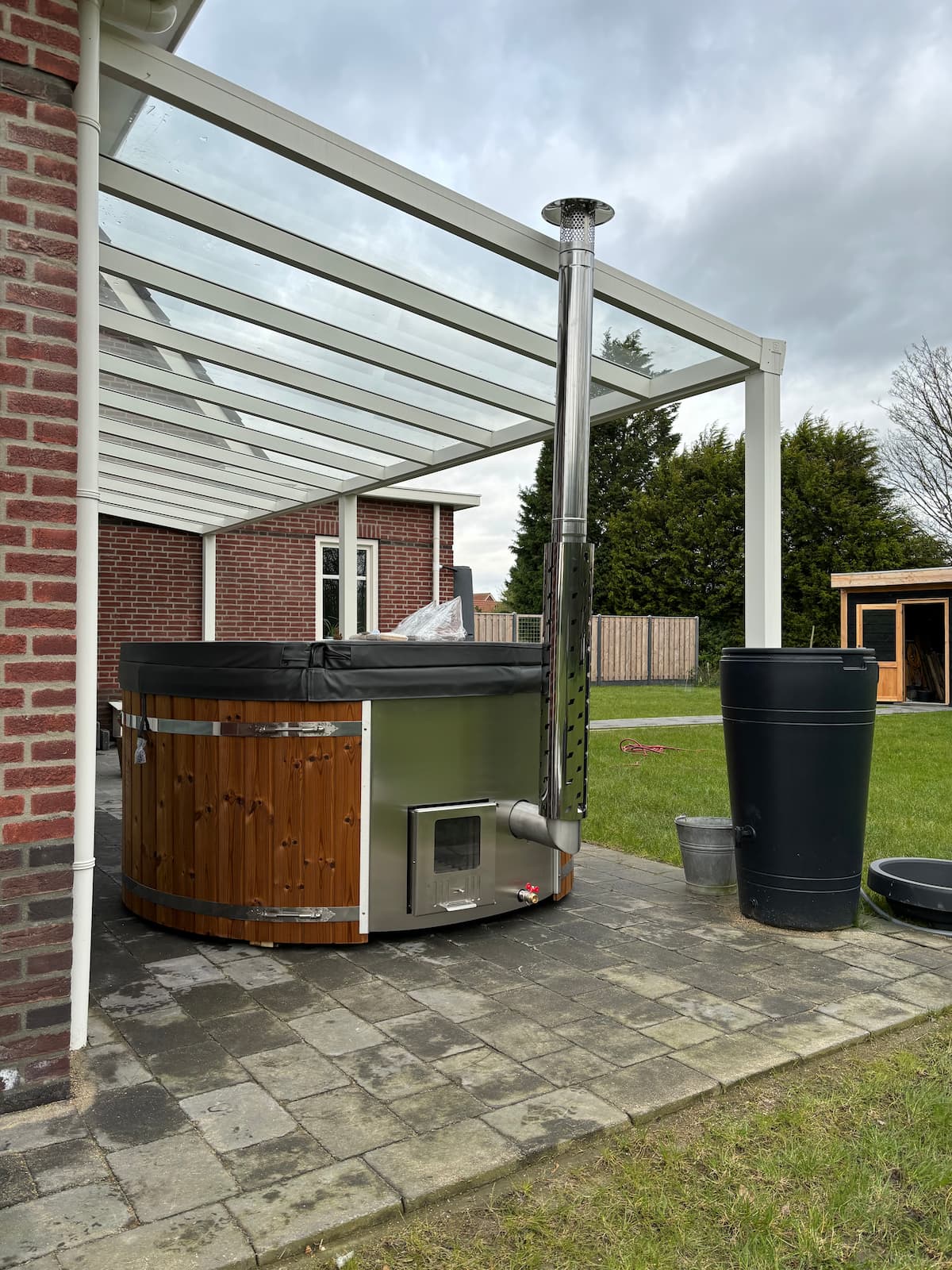Hottub model Vatten Stor met interne houtkachel, RVS banden, antraciet schaal, thermowood en trap. Afgedekt met een geïsoleerde cover.